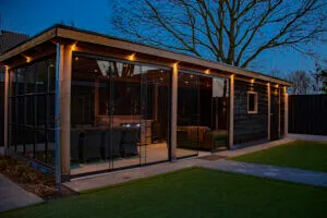 Verlichte houten pergola met lounge in een tuin van Bart de Bruin, bij schemering
