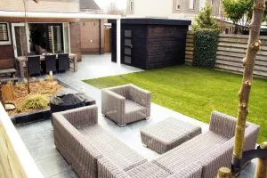 Bovenaanzicht van een tuin met loungeset, gazon en donkere tuinberging